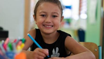 Enfant souriant avec un crayon